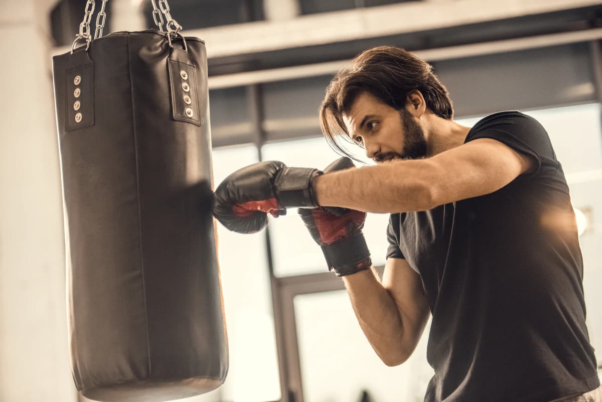Een bokser met bokshandschoenen slaat op een bokszak in een sportschool